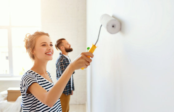 young happy couple is repairing and painting   wall at home.