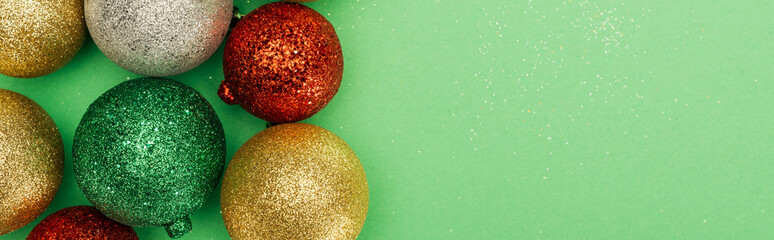 top view of colorful shiny christmas baubles on green background, panoramic shot
