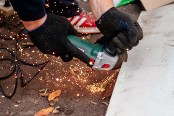 A man works with an angle grinder. Cuts metal.