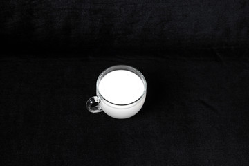 Glass mug with milk on black background