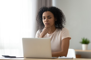 Pensive biracial woman thinking working on laptop - Powered by Adobe