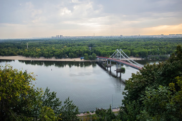 Tour of Kiev in the center of Europe. View of the Dnieper, Trukhanov island and a foot bridge. Park fountain and sunset on the horizon..