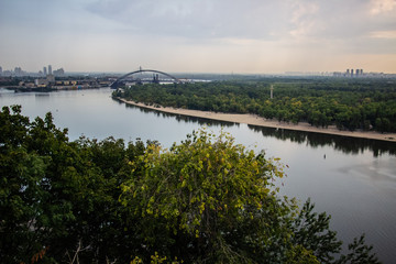 Tour of Kiev in the center of Europe. View of the Dnieper, Trukhanov island and a foot bridge. Park fountain and sunset on the horizon..