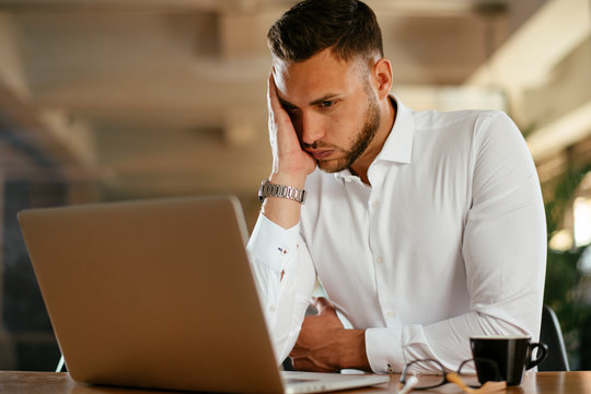 Tired businessman working on laptop in office