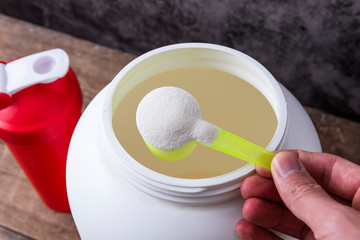 Sport nutrition supplement containers with shaker. Close up of protein powder and scoop