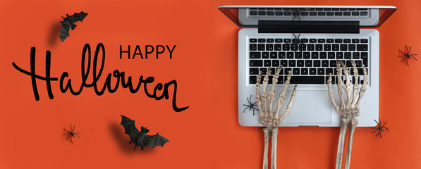 Skeleton hands typing in laptop and Happy Halloween text
