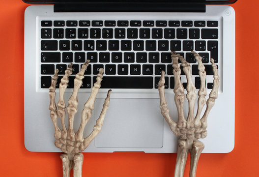 Skeleton hands typing on laptop