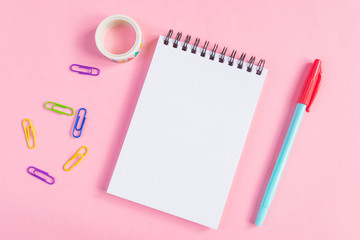 Pen, paper clips, notebook on a pink background. Place for text, minimalism. School, office, education concept.