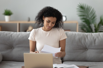 African American woman reading letter with good news at home