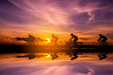 Fototapeta na wymiar Silhouette of cyclist with friend in motion on the background of beautiful sunset