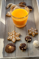 Group various kinds of delicious sweet Christmas cookies on light gray wood, fresh orange juice, tasty holiday breakfast