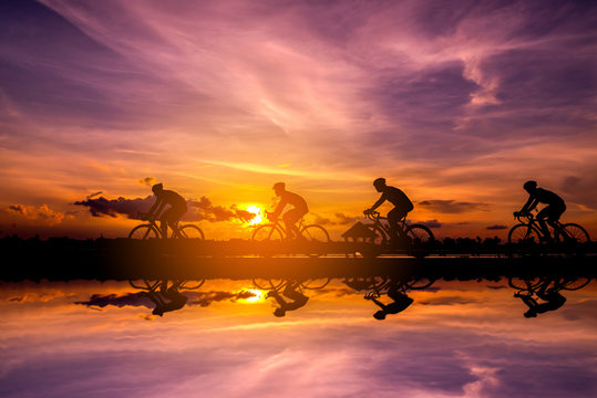 Silhouette of cyclist with friend in motion on the background of beautiful sunset