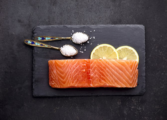 Salmon fish on the stone with lemon and salt. Top view