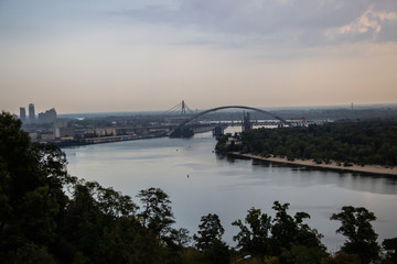 Obraz premium Tour of Kiev in the center of Europe. View of the Dnieper, Trukhanov island and a foot bridge. Park fountain and sunset on the horizon..