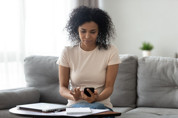 African American woman busy using smartphone at home