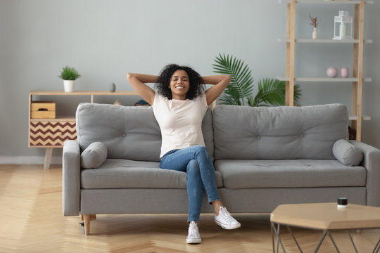 Happy black girl relaxing on cozy sofa at home