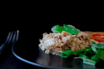 Tuna salad placed on a black plate with a side dish on a black background is a healthy food that most people eat to lose weight.