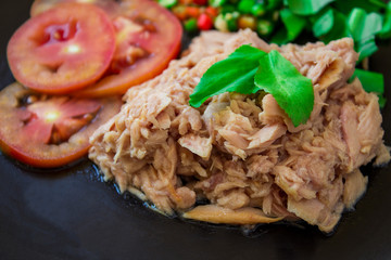 Tuna salad placed on a black plate with a side dish on a black background is a healthy food that most people eat to lose weight.