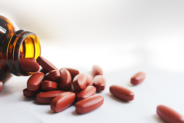 A bottle of calcium dietary supplements with a pill spilled out on a white background