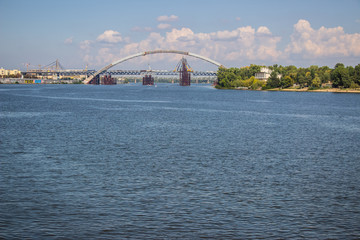 Naklejka premium Tour of Kiev in the center of Europe. View of the Dnieper, Trukhanov island and a foot bridge. Park fountain and sunset on the horizon..