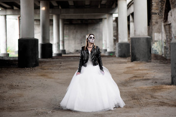 Obraz premium Portrait of zombie woman with painted skull face under a bridge.