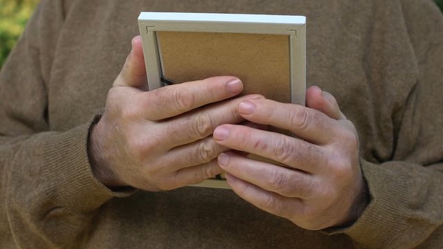 Aged male hugging photo missing children, sad widower remembering wife nostalgia