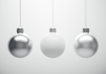 Glossy metallic christmas baubles hanging in front of white background.