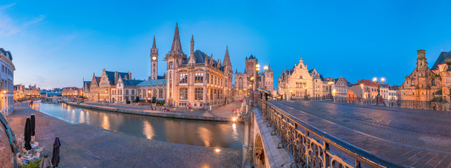 Fototapeta na wymiar Panoramic view of the Graslei, quay in the promenade next to river Lys in Ghent, Belgium and St Michael's Bridge at dusk. Gent old town is famous for its beautiful illuminated buildings and landmarks
