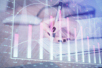 Multi exposure of hands making notes with forex chart huds. Stock market concept.