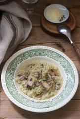 Traditional italian dish risotto with champignons in a light plate on a wooden table. Rustic style.