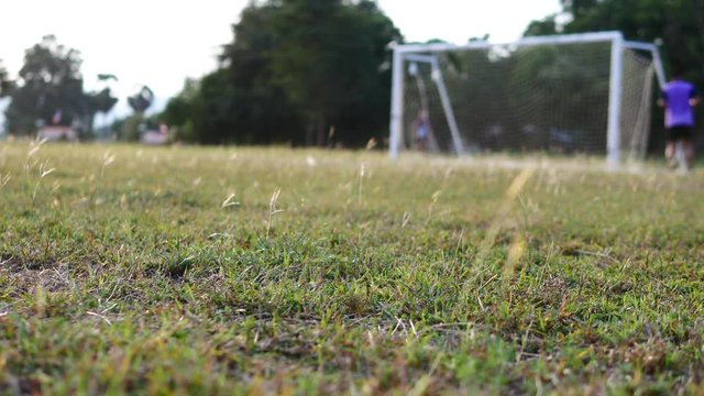 The Asian children are plying football in the glass field.