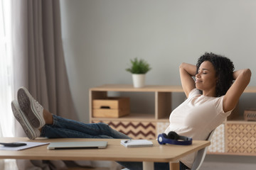 Happy black woman relax in chair at desk at home - Powered by Adobe