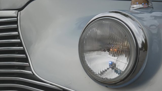 headlight of an antique light blue retro car flashing