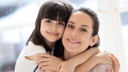 Close up headshot portrait young single happy mommy embracing daughter.