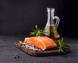 Salmon fish on the stone with rosemary and salt on black stone. Fish with spices.