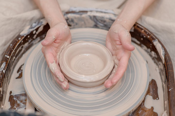 Close up womans hands make clay bowl in the workshop