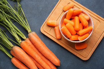 Bowl with fresh carrots on dark background