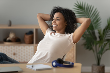 Happy biracial girl relaxing in chair dreaming at home