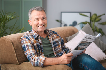 Portrait of stylish mature man with newspaper resting at home