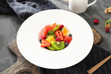 Plate with tasty fruit salad on table