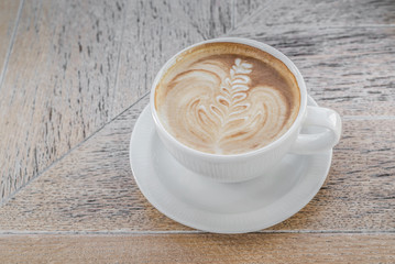White big cup of delicious coffee with art on wooden table with copy space.