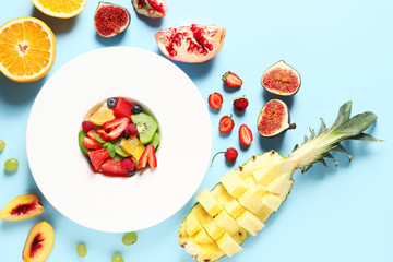 Plate with tasty fruit salad on color background