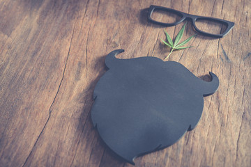 The masculine mustache and glasses with the cannabis leaf beside the old wooden floor.