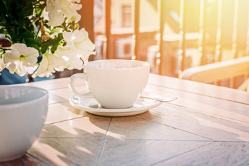 White big cup of delicious coffee on wooden table in sunset light with copy space.