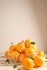 Basket with fresh oranges on white table