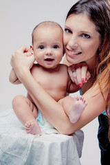 Close up portrait of beautiful young mother and her baby. grey background