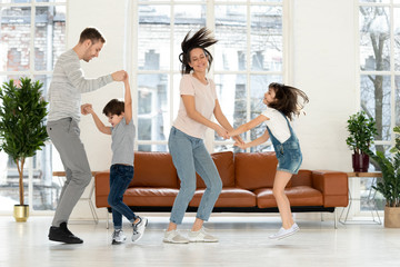 Overjoyed active parents dancing with happy kids.