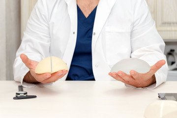 Doctor holding silicone implant for breast augmentation, space for text. Plastic surgeon hands...