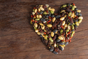 Whole grains that form a heart shaped pile on a dark brown wood floor.