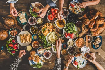 Foto op Plexiglas Turkse ontbijttafel. Plat leggen van de handen van mensen die gebak, groenten, groenten, olijven, kazen, gebakken eieren, jam, honing, thee in koperen pot en tulpenglazen nemen, bovenaanzicht. Midden-Oosterse maaltijd © sonyakamoz